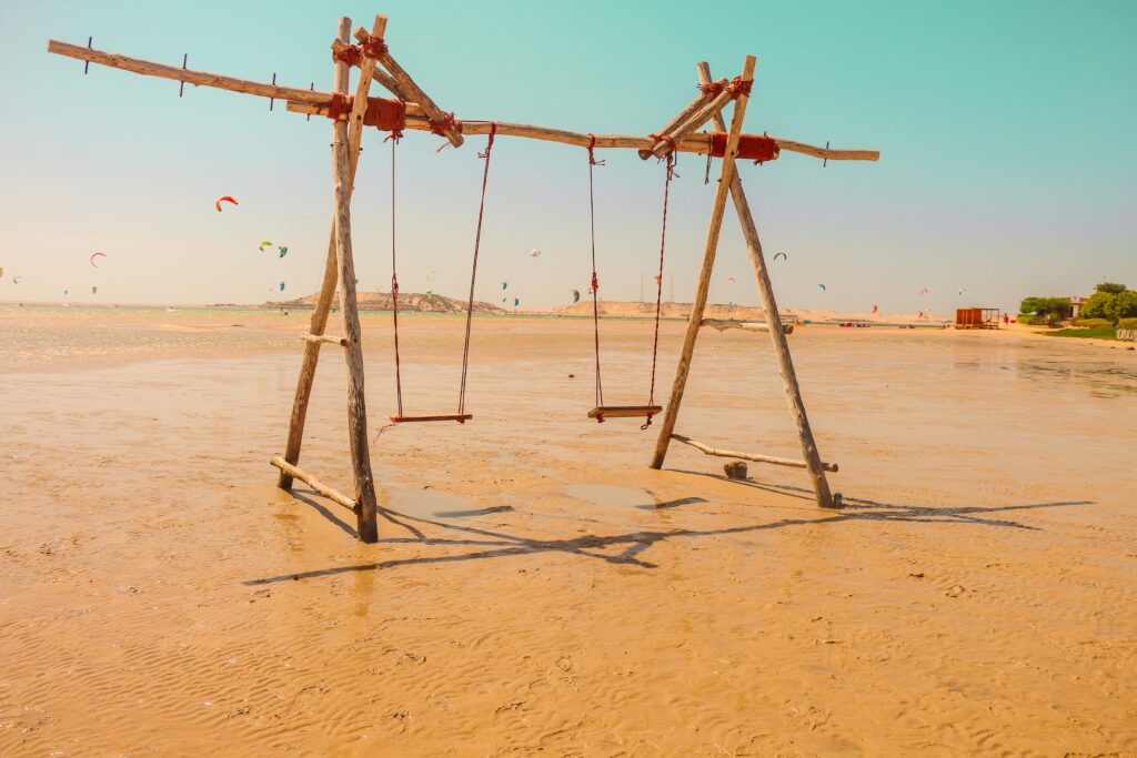 Balançoires sur la plage de Dakhla, kitesurfeurs au loin