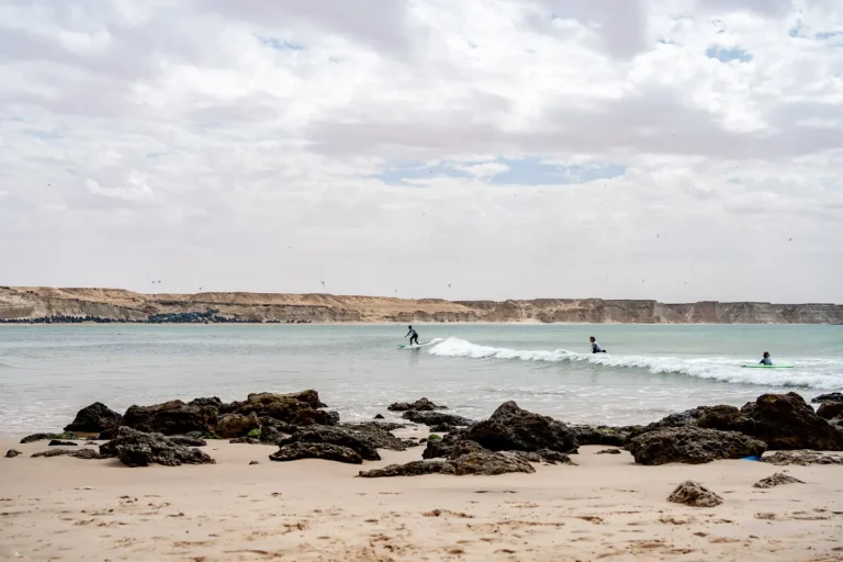 Surfeurs sur une vague dans une baie de Dakhla, falaises en arrière-plan
